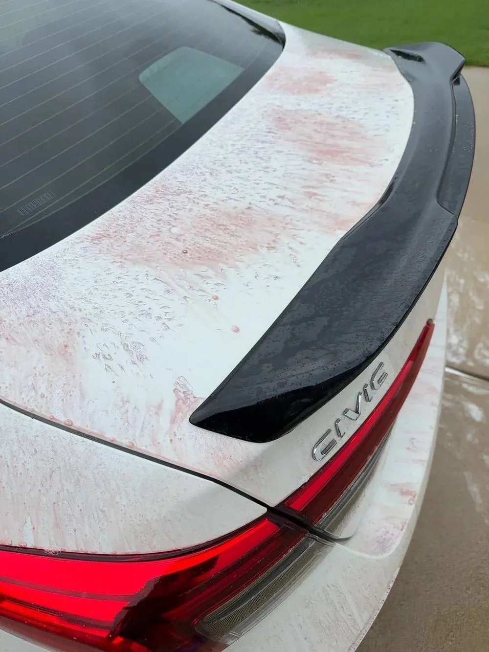 Iron fallout remover reacting purple as it dissolves embedded iron from the paint of a white Honda Civic