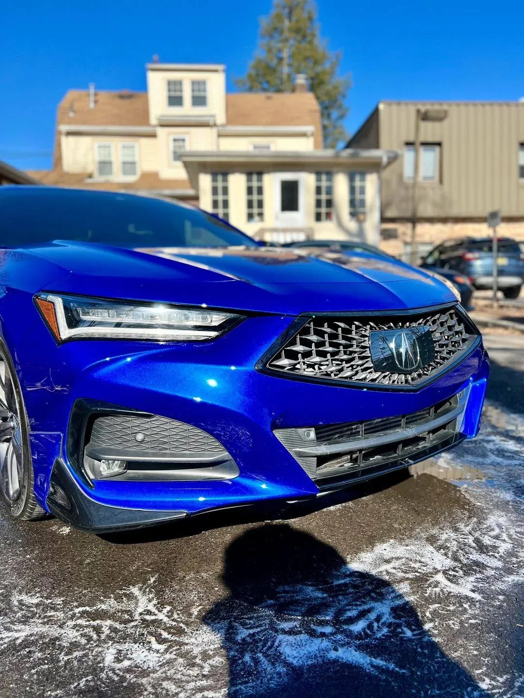 Blue Acura TLX being washed, snow foam running off the front bumper